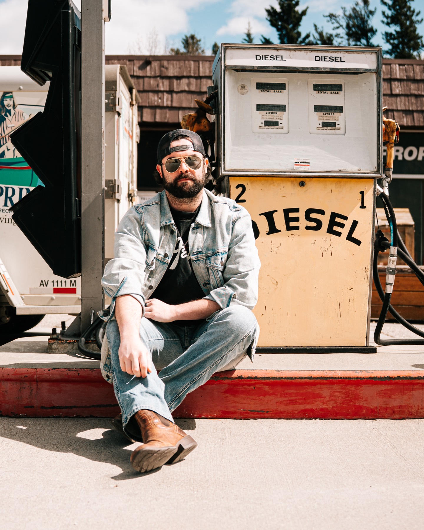 Dean James seated beside a weathered diesel pump on the road